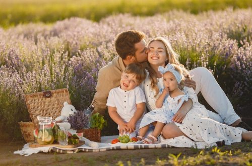 A joyful family enjoying a picnic together in a scenic lavender field during summer.